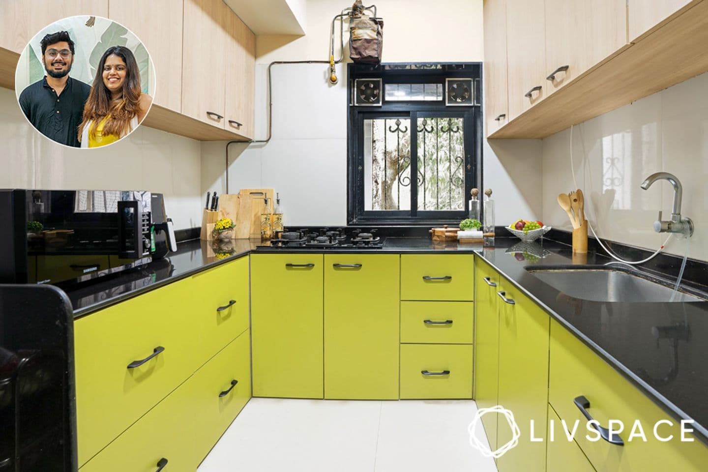 Kitchen with green lower cabinets, pale wood upper cabinets and a black stone counter